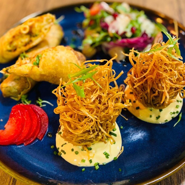 noodle fritters, spring rolls, salad, & pickled garnish served at Who’s 
Café. 